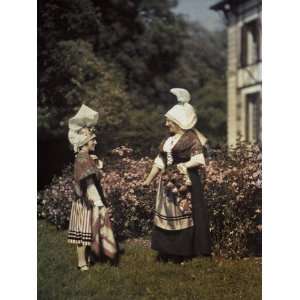 Two Women Interacting in a Garden Don Elaborate Headdresses Stretched 